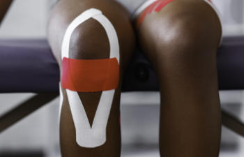 Person With Kinesiology Tape Applied Over Their Knee