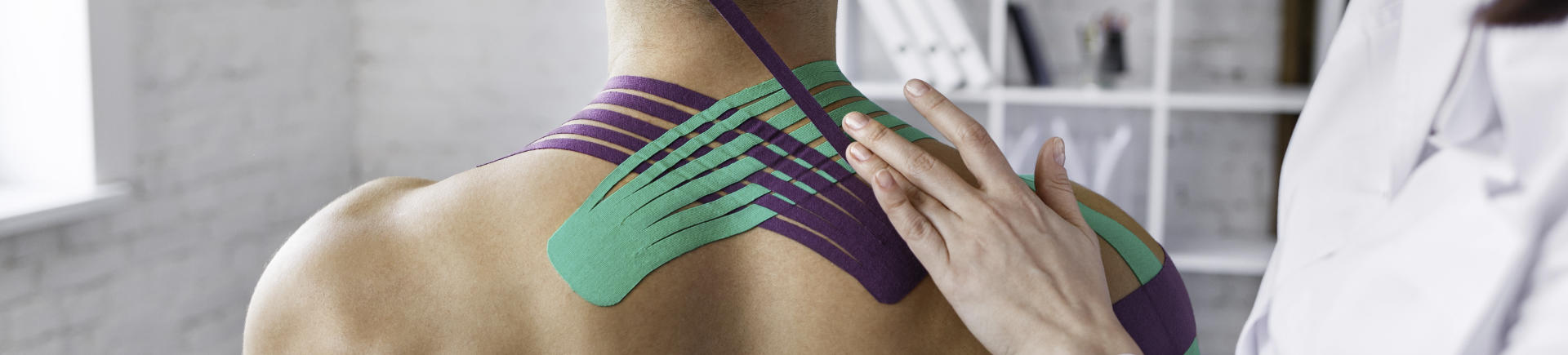 Rehab Specialist Applying Kinesiology Tape Over Patient's Neck and Shoulder