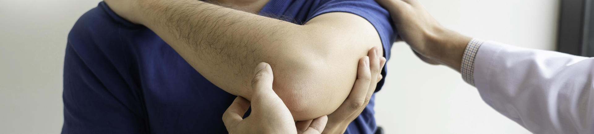 Chiropractor examining a young man with shoulder injury