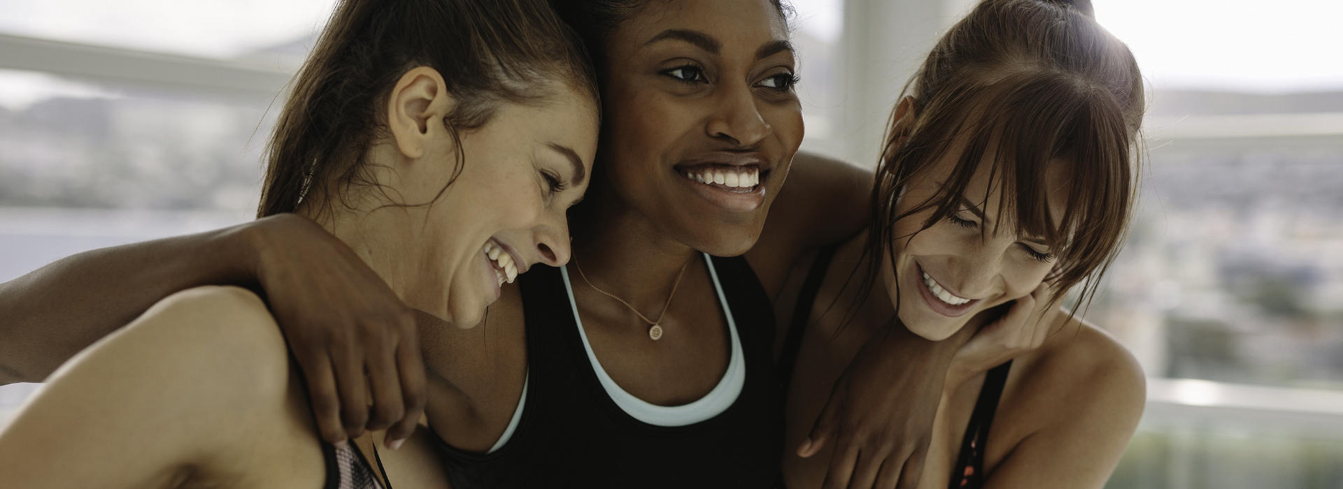 three haappy sportswomen hugging each other