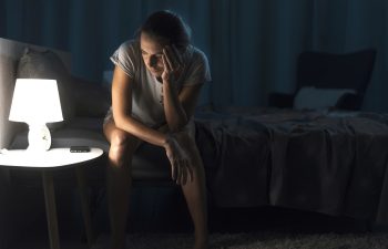 Exhausted woman suffering from insomnia, she is sitting on the bed and thinking